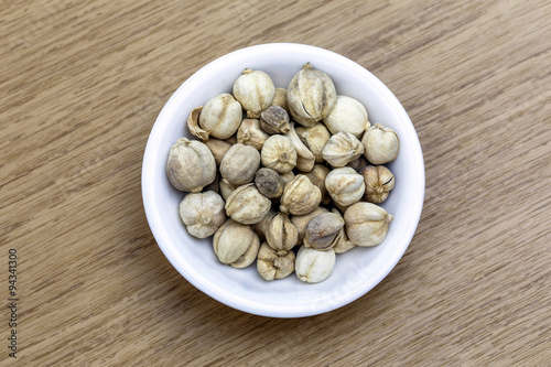 Dry cordamon in white bowl on wooden table photo