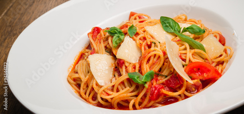 Spaghetti with tomato, parmesan and basil served in a white plate