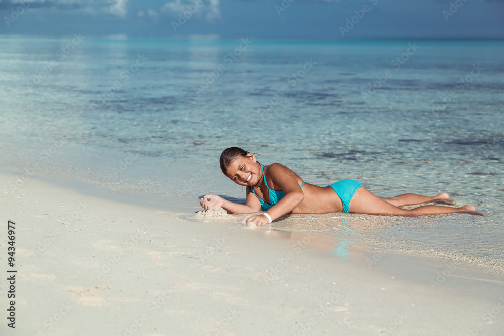 funny happy joyful little girl lying, playing and relaxing in the ocean at early morning, on tropical Cuban beach