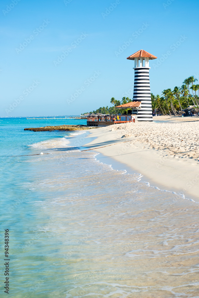 Fototapeta premium Beautiful day at sea. White sand, tropical palm trees and lighthouse on sandy shore