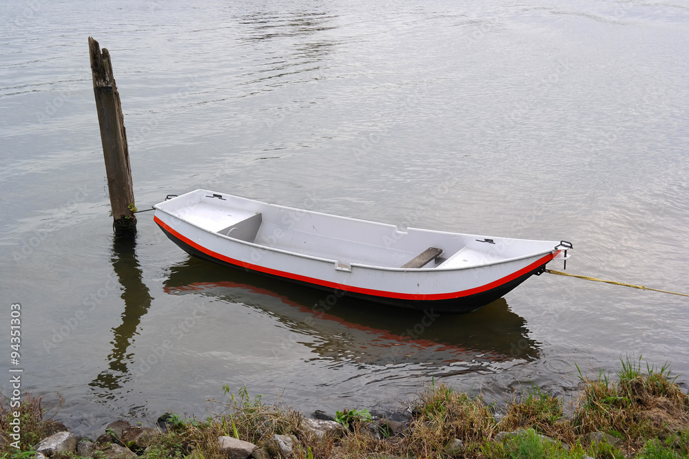 Naklejka premium Old-fashioned moored iron row boat on Maas river in The Netherlands