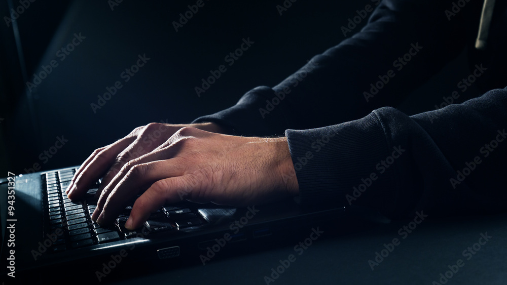 Man hands typing on laptop computer keyboard black background