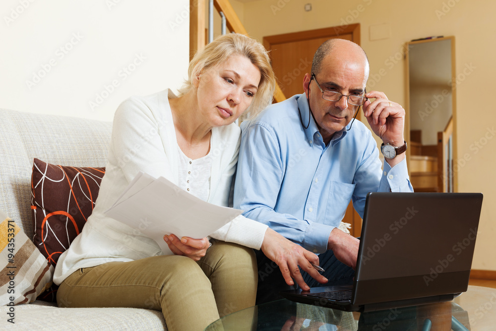  mature couple with financial documents and laptop