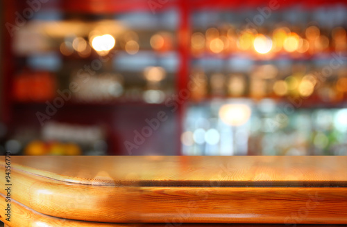 image of wooden table in front of abstract blurred background of restaurant lights  