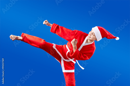 Girl in Santa Claus clothes makes high kick karate