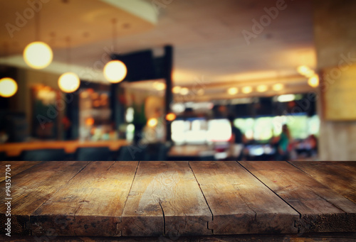 Fotografia image of wooden table in front of abstract blurred background of restaurant ligh