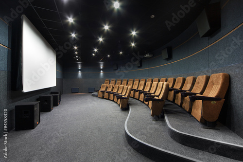 Interior of a small theater with orange chairs and screen