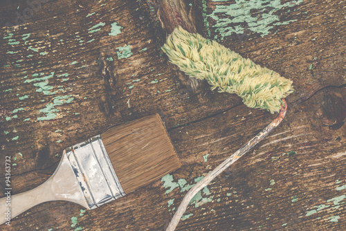 Old paintbrush and paint roller on rustic wooden board photo