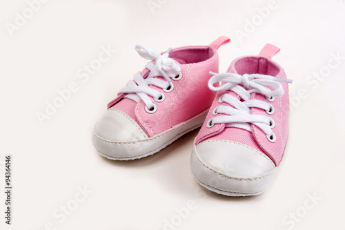 Cute pink baby girl sneakers close up on gray background