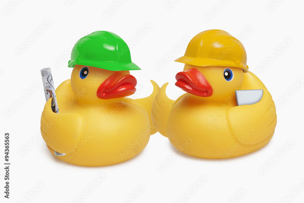 Two construction worker rubber ducks shake wings at a site meeting Two construction worker rubber ducks shake wings at a site meeting