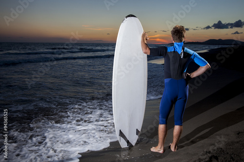 Young male surfer  on  beach in sunset