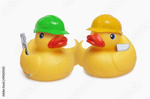 Two construction worker rubber ducks shake wings at a site meeting