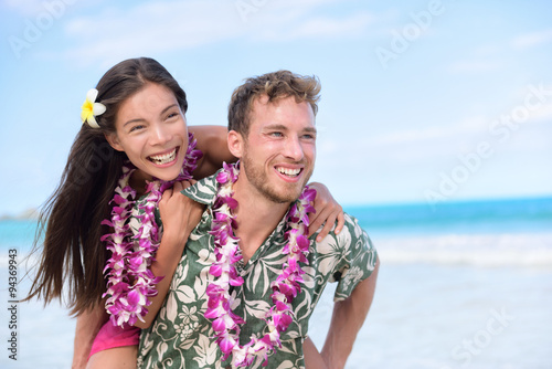 Happy beach couple having fun piggybacking