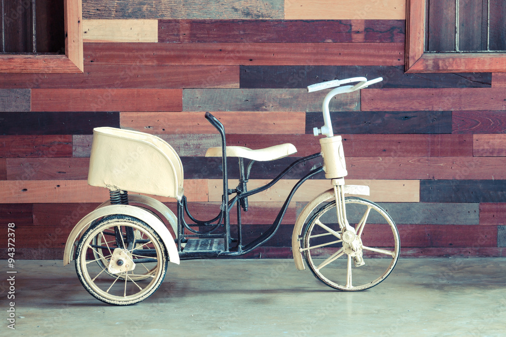 old classic tricycle for baby with wood background