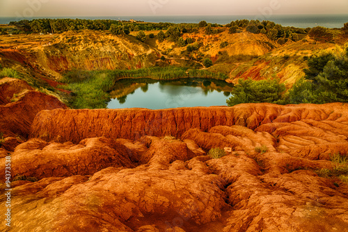 red soils around the lake in bauxite quarry photo