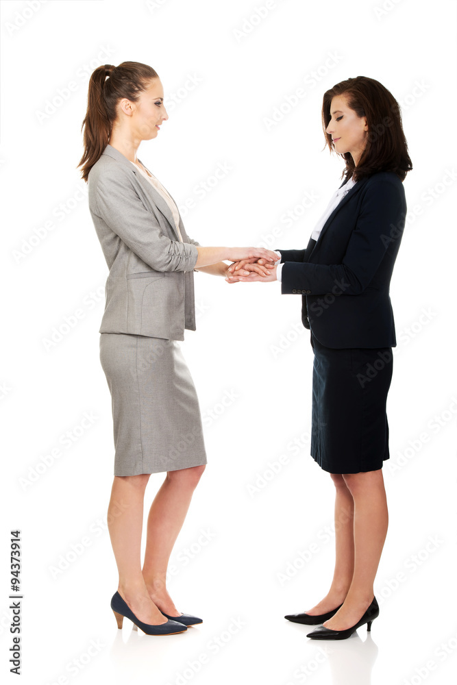 Two businesswomen holding their hands together. Two businesswomen holding their hands together.