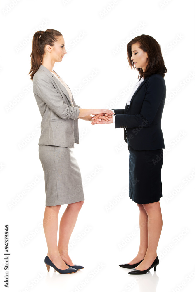 Two businesswomen holding their hands together. Two businesswomen holding their hands together.