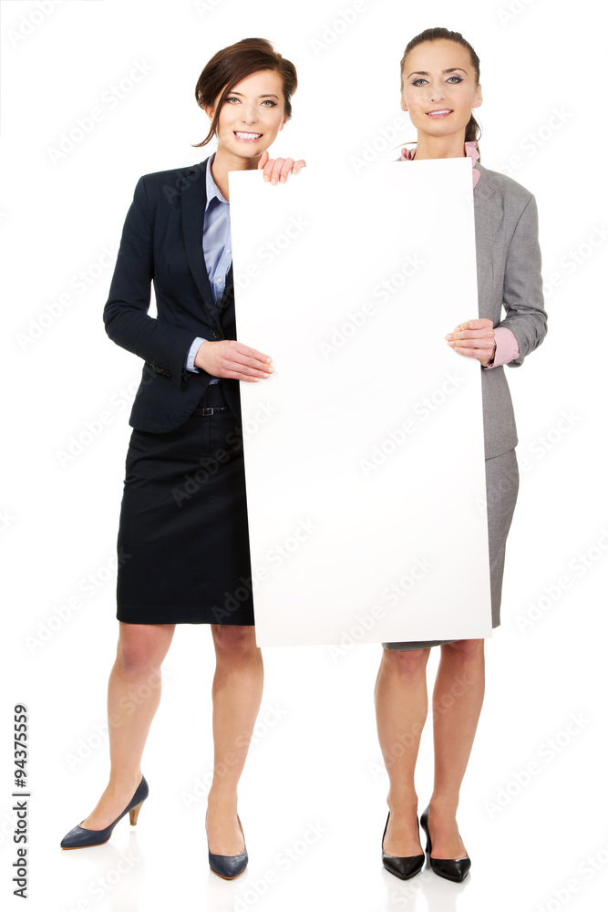 Two businesswomen carrying a big white board. Two businesswomen carrying a big white board.