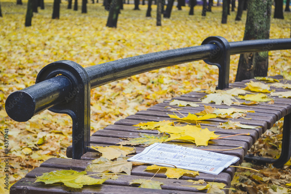 Golden autumn. Beautiful maple leaves and newspaper on a bench in October. Kiev, Ukraine Golden autumn. Beautiful maple leaves and newspaper on a bench in October. Kiev, Ukraine