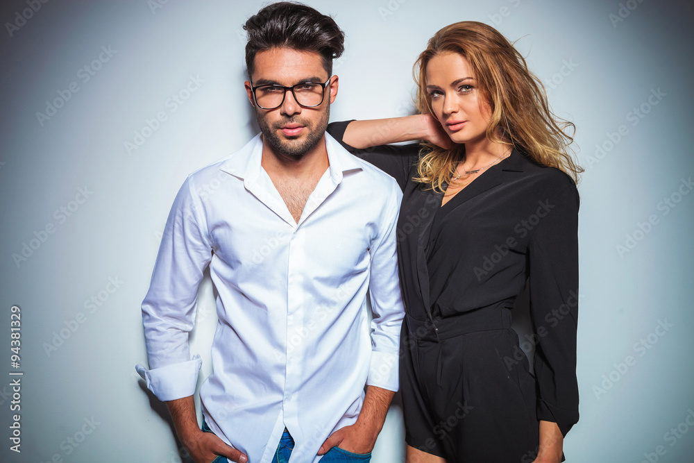 man pose with hands in pockets while woman rests her arm on his man pose with hands in pockets while woman rests her arm on his