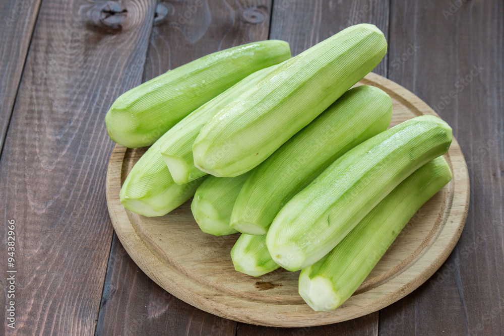 peeled zucchini on cutting board at wooden background