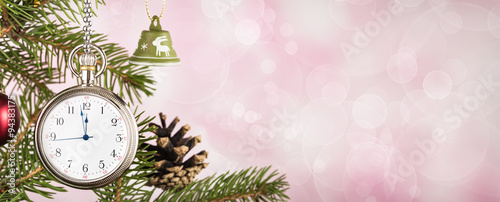 Pocket watch on Christmas tree branch on pink background