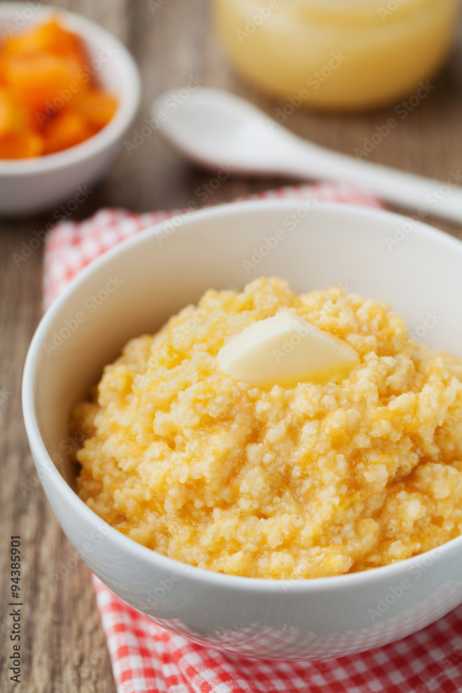 Millet porridge with baked pumpkin and butter in bowl on wooden table, baby food Millet porridge with baked pumpkin and butter in bowl on wooden table, baby food