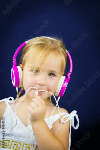Beautiful little girl with headphones on her ears
