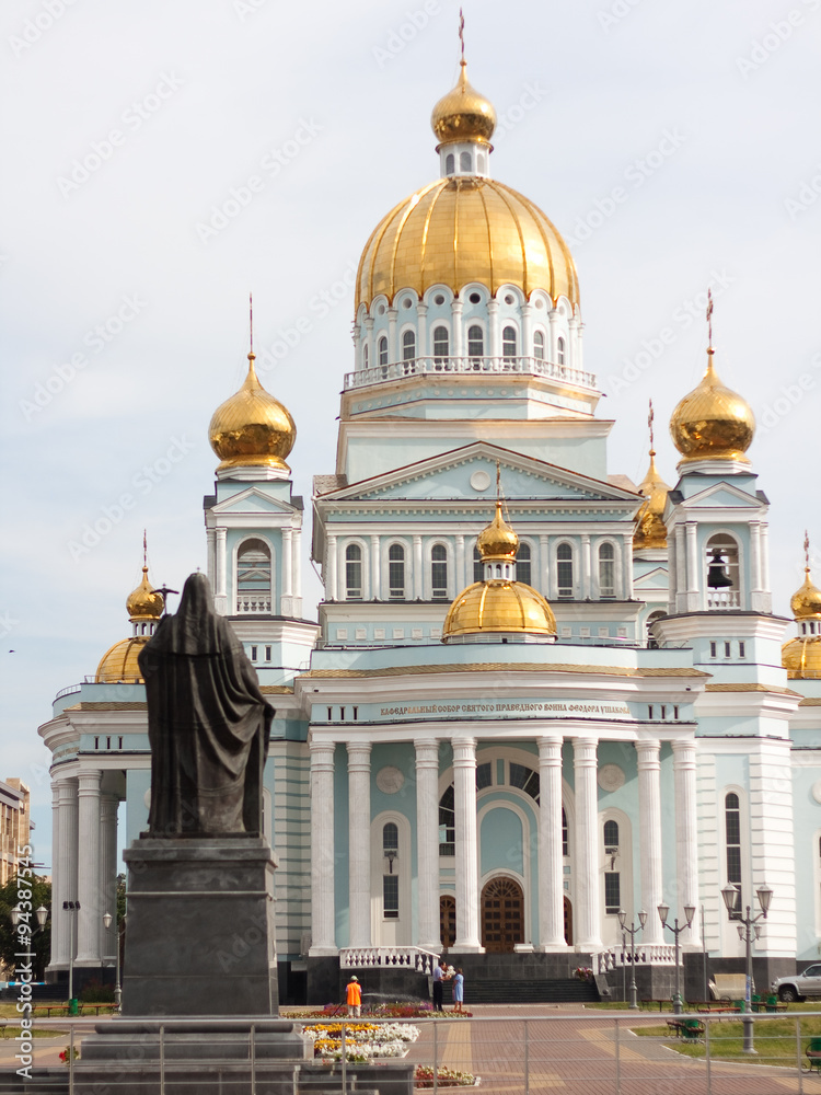 Monument on the background of white orthodox church Cathedral of Saint righteous warrior Feodor Ushakovwith gold domes