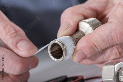 Plumber putting a teflon joint on a thread photo