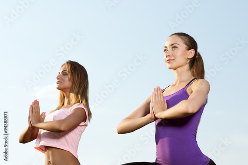 Two beautiful girls meditating outdoors