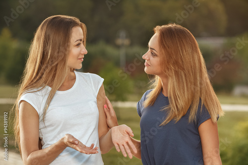 Two young girls having conversation outdoor
