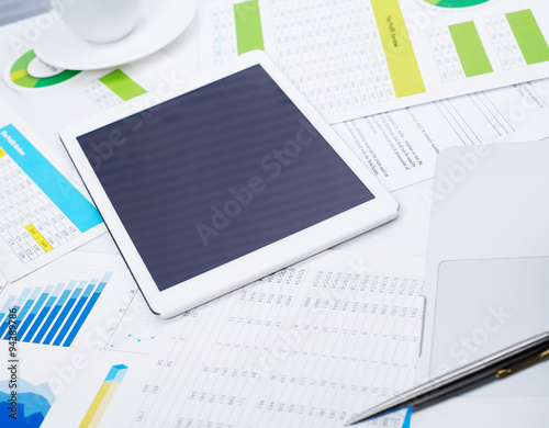 Tablet on desk and financial papers