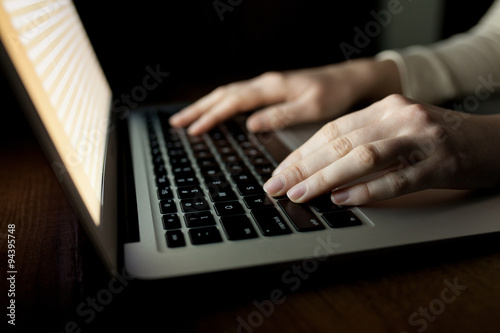 woman hands using laptop at office desk, with copyspace in dark