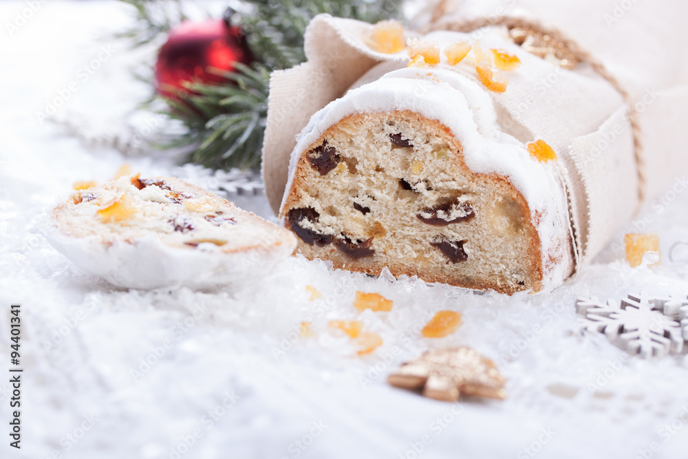 German dresdner stollen cake with raisins and candied oranges on a white background with false snow.