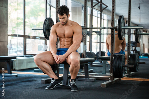 Man resting on the bench in fitness gym