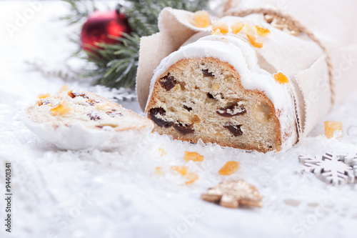 German dresdner stollen cake with raisins and candied oranges on a white background with false snow.