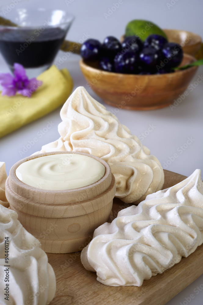 Close up of some meringues, with a bowl of cream in the middle Close up of some meringues, with a bowl of cream in the middle
