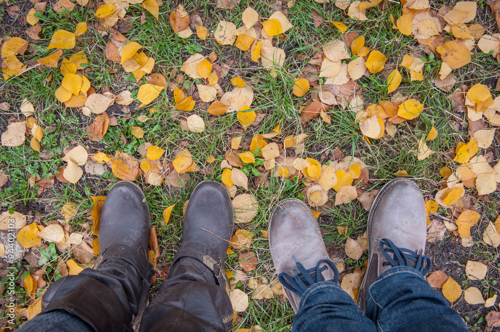 Conceptual image of legs in boots on the autumn leaves. Feet shoes walking in nature Conceptual image of legs in boots on the autumn leaves. Feet shoes walking in nature
