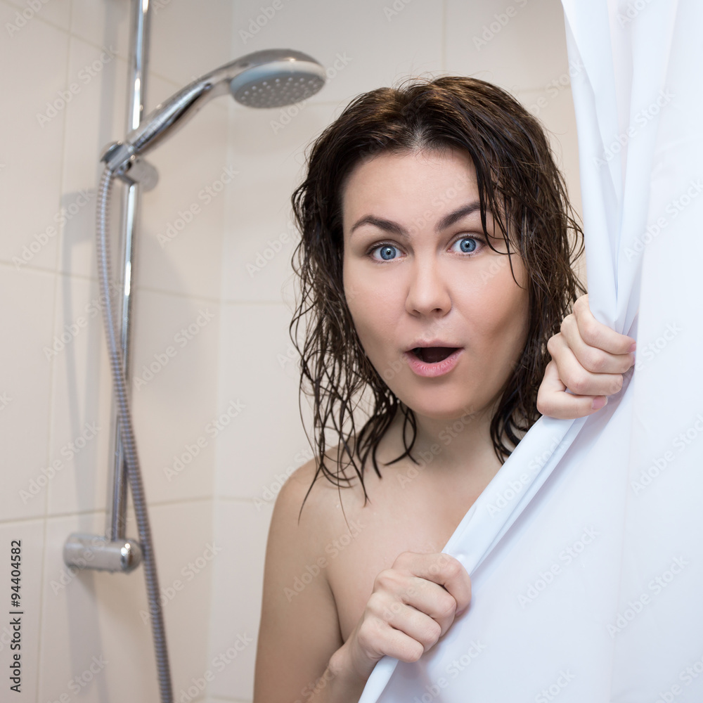 beautiful shocked woman covering her body with curtain in shower Stock