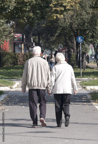 Rear view of senior couple walking down in park and chatting