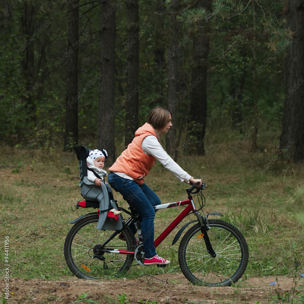 mother and daughter riding bike in the forest