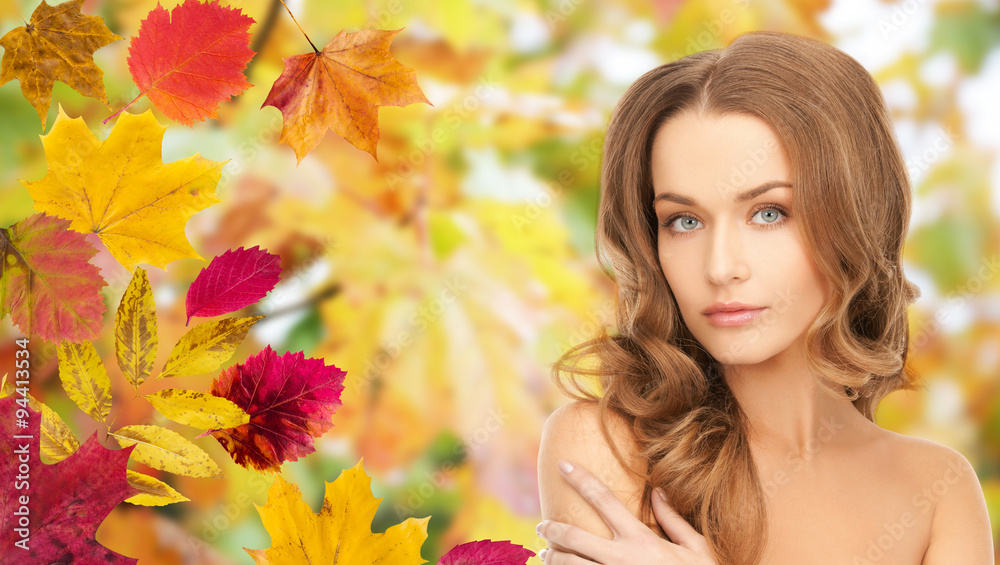 beautiful young woman face over autumn leaves