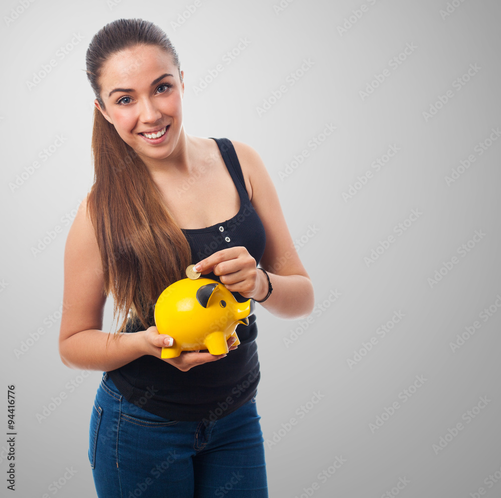 portrait of a pretty girl saving inserting coin in a piggy bank portrait of a pretty girl saving inserting coin in a piggy bank