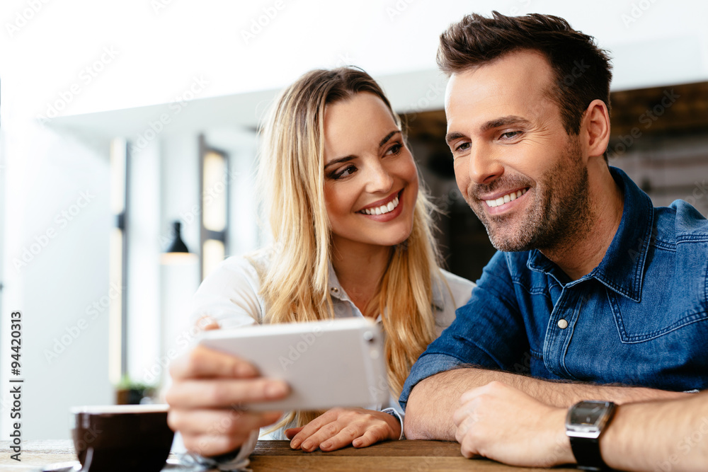 Happy friends looking at smartphone at cafe Happy friends looking at smartphone at cafe