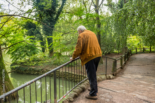 Fotografía Senior leaning against railing watching  pond