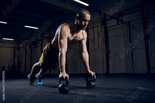 Athlete making push ups on kettlebells for better strength