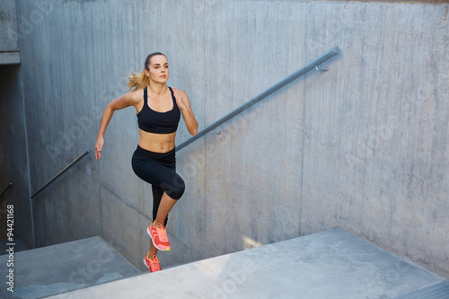 Athletic woman running up stairs photo