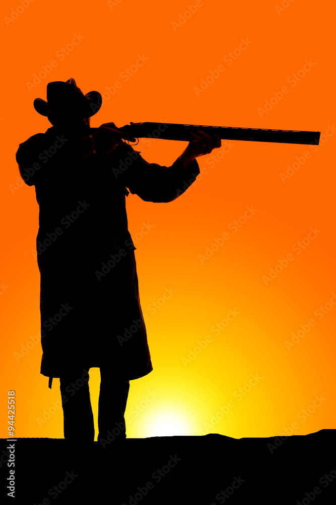 silhouette of cowboy in coat aiming a gun