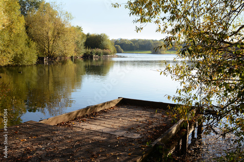 Wooden jetty in fall looks out over a lake photo